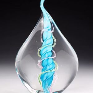 Dual flame glass memorial infused with cremation ash, featuring an aqua twisted core accented with pink and green strands inside a clear teardrop form.