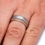 Solid gold memorial ring with meteorite inlay and cremated ashes worn on finger