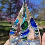 Handmade glass pyramid memorial with cremation ash in aqua, blue, and green.
