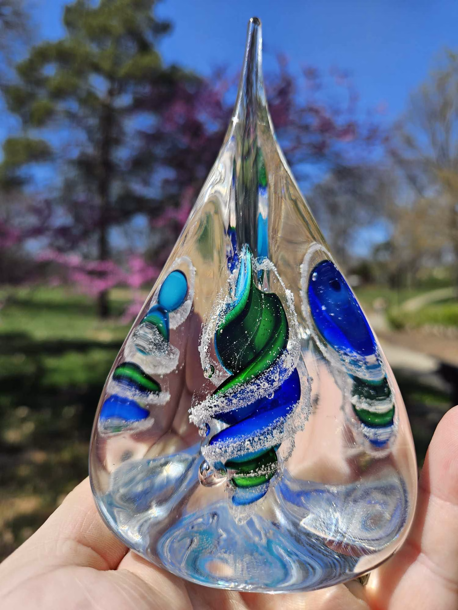 Handmade glass pyramid memorial with cremation ash in aqua, blue, and green.