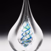 Teardrop memorial glass keepsake with cremation ash, showcasing a clear hand-blown teardrop form with intertwined blue and green spiral glass suspended inside the inner chamber, photographed upright against a dark studio background.