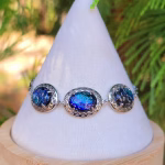 Filigree triple stone cremation ash bracelet in sparkling blue glass, set in sterling silver and displayed on a white jewelry stand