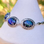 Side view of filigree triple stone cremation ash bracelet in sparkling blue tones, set in sterling silver with oval glass stones