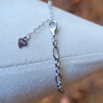 Close-up of the clasp and extension chain on the dragonfly cremation bracelet, showing a sterling silver lobster clasp and heart-shaped S925 tag on a white jewelry display.
