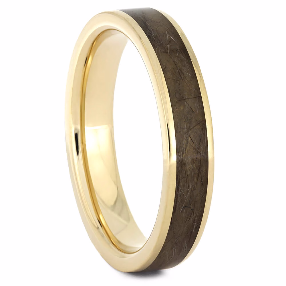 Gold memorial ring with hair or fur inlay, angled view showing polished gold band and preserved keepsake material set flush within the ring