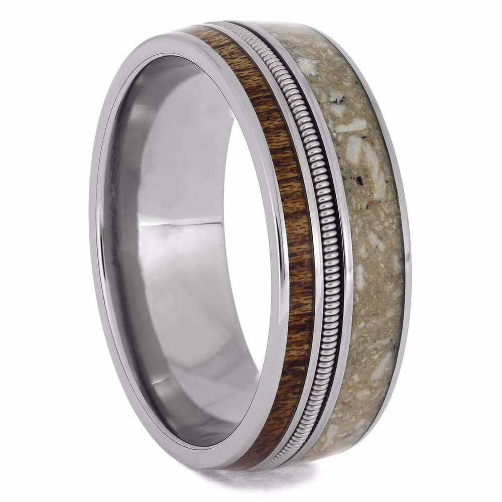 Angled view of cremation ring with ashes featuring guitar string inlay, mahogany wood band, and polished titanium memorial ring