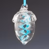 Hand-blown glass acorn memorial ornament featuring a clear acorn shape with a vibrant aqua spiral infused with cremation ash, suspended from an aqua ribbon against a soft gray background.