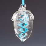 Hand-blown glass acorn memorial ornament featuring a clear acorn shape with a vibrant aqua spiral infused with cremation ash, suspended from an aqua ribbon against a soft gray background.