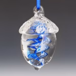 Hand-blown glass acorn memorial ornament featuring a clear acorn shape with a vibrant blue swirling spiral infused with cremation ash, suspended from a blue ribbon against a soft gradient background.