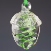 Hand-blown glass acorn memorial ornament featuring a clear acorn shape with swirling green coloration infused with cremation ash, hanging from a green ribbon against a dark background.