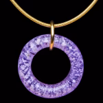 Amethyst halo cremation pendant with encased cremation ash on gold necklace displayed on black background