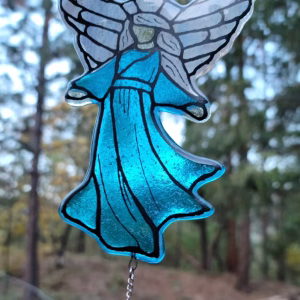 Guardian Angel suncatcher made with cremation ash, featuring translucent blue stained glass robes, silver-toned angel wings, and a hanging crystal accent, photographed outdoors in natural light.