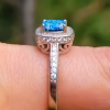 Side view of the Cremation Ring with Square Halo Band, showing the raised blue silver crinkle glass center stone secured by prongs, with cubic zirconia accent stones along the halo and down the silver band.