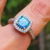 Cremation Ring with Square Halo Band worn on a finger, featuring a blue silver crinkle glass center set in a square halo of cubic zirconia stones on a silver band.