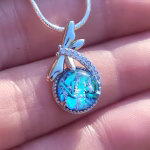 Silver dragonfly cremation pendant with blue crinkle glass and visible cremation ash.