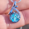Silver dragonfly cremation pendant with blue crinkle glass and visible cremation ash.