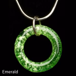 Halo Cremation Pendant in emerald green, featuring a rich green glass ring with lighter ash inclusions, suspended from a silver chain against a black background.