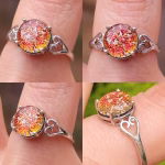 A four-image collage showing a sterling silver Heart Cremation Ring with a round red orange memorial glass stone infused with cremation ash. The stone displays shimmering tones of red, orange, and gold. Each image highlights different angles of the ring, including the prong setting, the iridescent glass detail, and the delicate heart-shaped filigree on the band. The ring is shown worn on a finger in natural outdoor light.