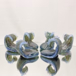 Crashing Wave Memorial Keepsake with cremation ash in blue, seafoam green, and clear glass, shown in a wide group view on a mirrored studio surface highlighting multiple wave forms