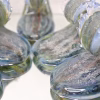 Crashing Wave Memorial Keepsake with cremation ash in blue, seafoam green, and clear glass, shown in a close-up group view highlighting the layered wave details on a mirrored studio surface