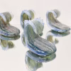 Crashing Wave Memorial Keepsake with cremation ash in blue, seafoam green, and clear glass, shown as a group of sculpted waves on a mirrored surface in a studio setting
