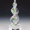 Aqua, pink, and green Legacy Flame cremation ash sculpture featuring a hand-blown glass design with swirling multicolor ribbons suspended in clear glass, set on a polished square glass base as a modern memorial keepsake.