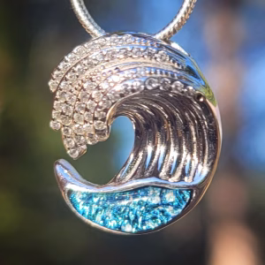 Ocean Wave Cremation Pendant in sterling silver featuring blue memorial glass beneath a sculpted wave design.