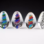 Eternity egg memorials made with cremation ash shown in multiple color variations.