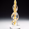 Gold Legacy Flame cremation ash sculpture featuring hand-blown clear glass with swirling golden accents, displayed on a polished glass base as an elegant memorial art keepsake.