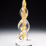 Gold Legacy Flame cremation ash sculpture featuring hand-blown clear glass with swirling golden accents, displayed on a polished glass base as an elegant memorial art keepsake.