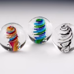 Three handcrafted Eternity Sphere memorials made with cremation ash, featuring suspended spiral glass designs in clear spheres, symbolizing continuity, remembrance, and eternal connection.