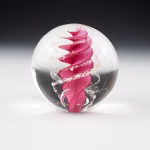 Handcrafted Eternity Sphere memorial made with cremation ash, featuring a rose pink spiral suspended in clear glass with fine ash inclusions gently following the curved design.
