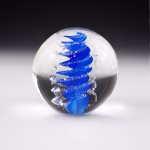 Handcrafted Eternity Sphere memorial made with cremation ash, featuring a bold cobalt blue spiral suspended in clear glass with fine ash inclusions following the flowing curves.