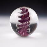 Handcrafted Eternity Sphere memorial made with cremation ash, featuring a deep purple spiral suspended in clear glass with fine ash inclusions following the flowing form.