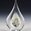 Teardrop memorial glass keepsake containing cremation ash, featuring a clear teardrop-shaped exterior with a colorful spiral design suspended inside, photographed upright against a dark studio background.
