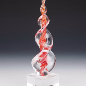 Red and orange Legacy Flame cremation ash sculpture featuring hand-blown clear glass with vibrant swirling red-orange accents, crafted as an elegant memorial art glass keepsake displayed on a polished glass base.