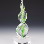 Green Legacy Flame cremation ash sculpture featuring a hand-blown clear-glass flame with vibrant green swirling accents, crafted as an elegant memorial art glass keepsake and displayed on a polished glass base.