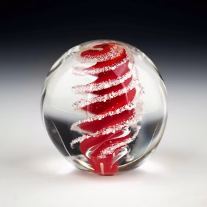 Handcrafted Eternity Sphere memorial made with cremation ash, featuring a rich red spiral suspended in clear glass with fine ash inclusions following the flowing spiral form.