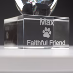 Close-up of an engraved glass memorial base featuring a paw print design with the name “Max” and the inscription “Faithful Friend.”