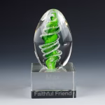 Handmade green eternity egg memorial with cremation ash displayed on an engraved glass base.