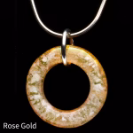 Halo Cremation Pendant in rose gold–toned glass with subtle pink, gold, and cream hues, suspended from a silver chain against a black background.