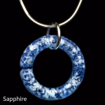 Halo Cremation Pendant in sapphire blue glass, shown on a silver chain against a black background.