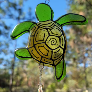 Handcrafted Turtle Suncatcher with Cremation Ash, featuring green stained glass turtle design with etched shell details and a hanging crystal prism, photographed outdoors against a natural background