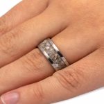 Polished titanium cremation ring with inlaid memorial ashes shown on hand
