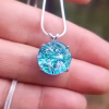 Sterling silver halo cremation pendant with aqua crinkle glass held on a silver chain.