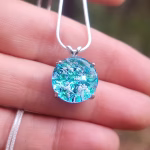 Sterling silver halo cremation pendant with aqua crinkle glass held on a silver chain.