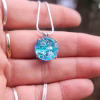Sterling silver halo cremation pendant with aqua crinkle glass held on a silver chain.