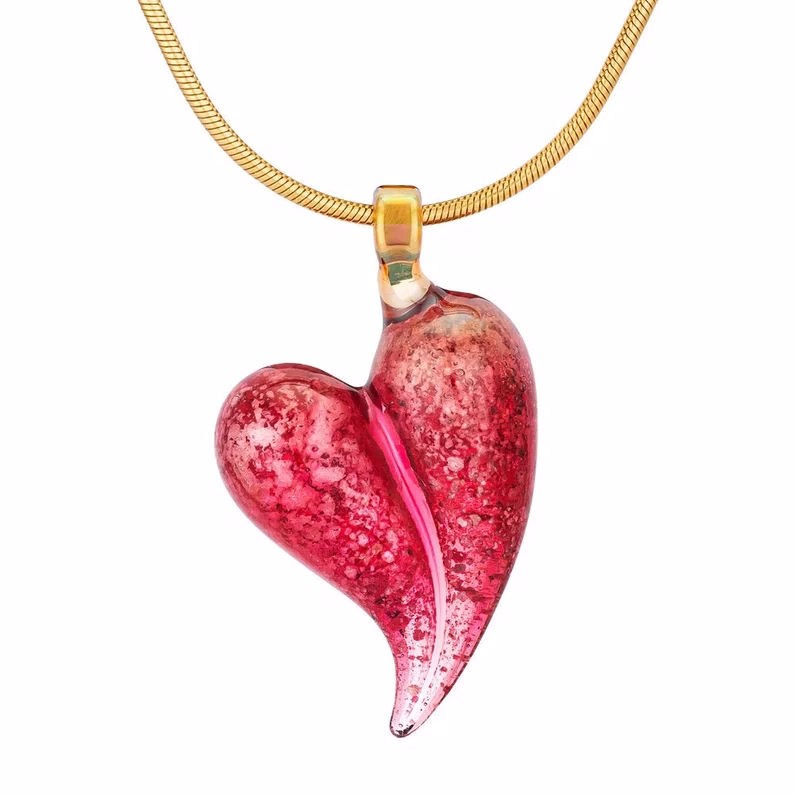 Handblown Tourmaline Memorial Heart cremation pendant featuring vibrant ruby-pink ash-infused glass with a flowing sculpted heart shape and a gold bail on a matching gold chain.