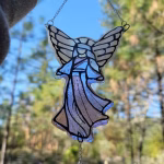 Guardian Angel suncatcher made with cremation ash, shown hanging by a chain and held gently by hand, featuring stained glass angel wings, flowing robes, and a crystal accent catching natural sunlight.