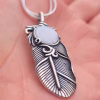 Close-up of the Boho Feather Cremation Pendant, featuring a silver feather memorial pendant with a white cremation ash glass cabochon resting in the palm of a hand
